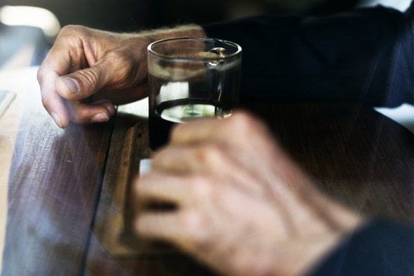 Hands holding a glass on a wooden table